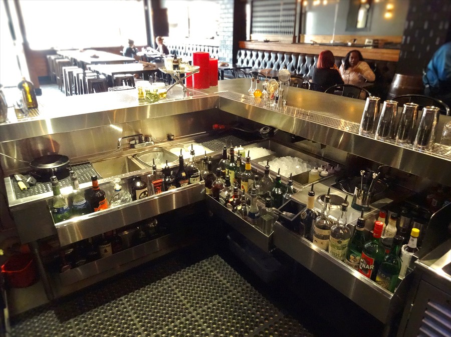 image of mixology station with bottles of alcohol in drink rail in restaurant setting